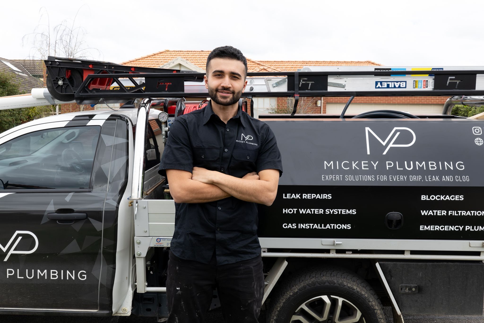 Murat from Mickey Plumbing standing in front of his work ute
