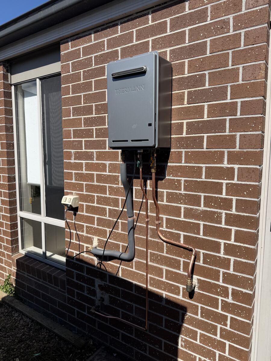 Continuous flow gas hot water unit installed on a brick wall