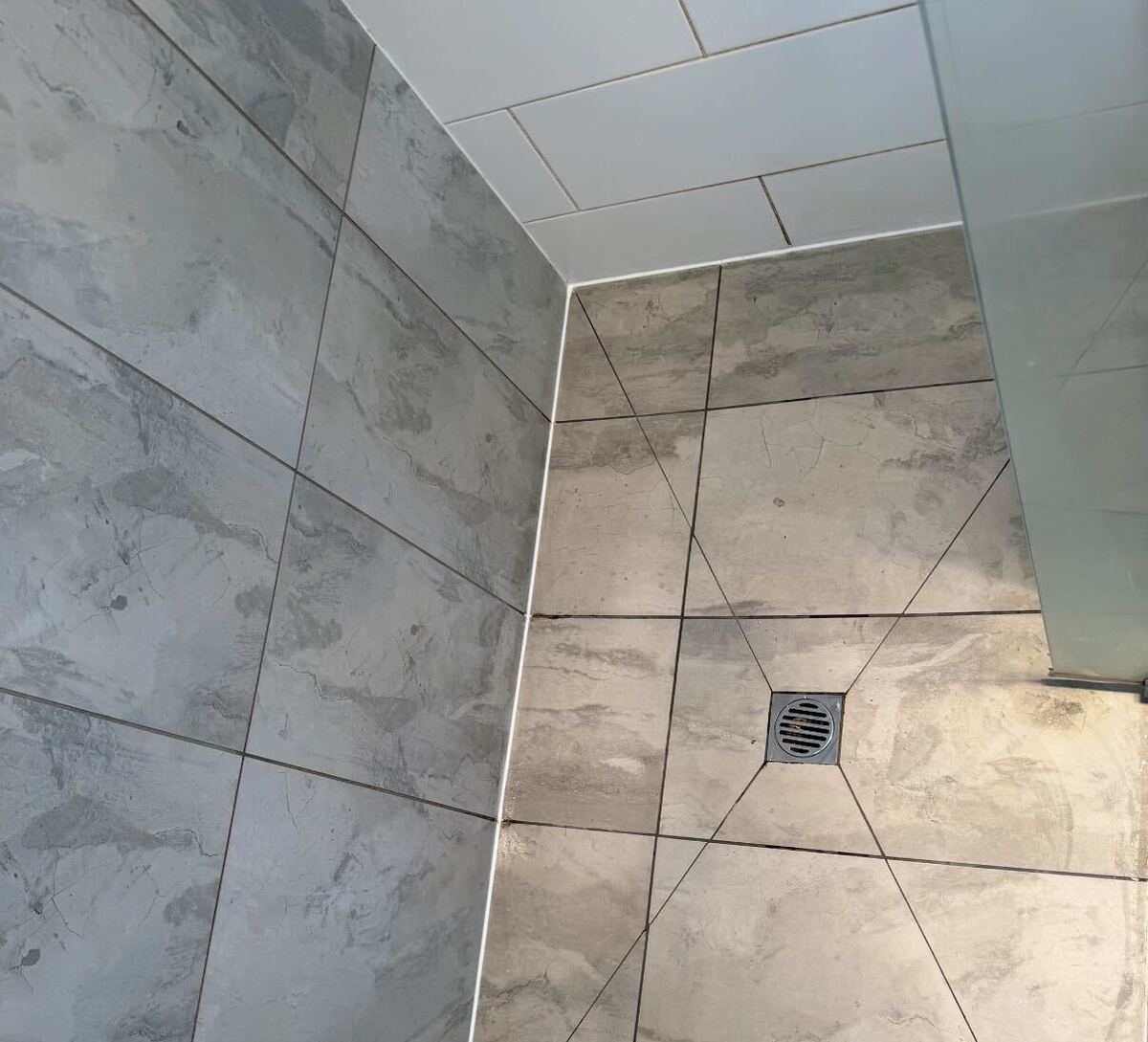 A freshly tiled and sealed shower with floor waste